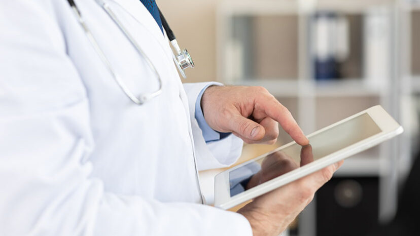 Side view of medical practitioner using digital tablet