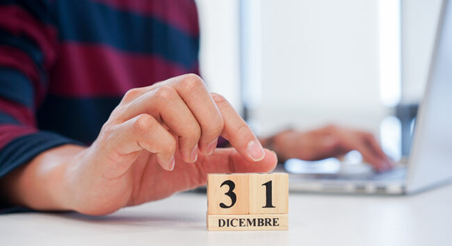 close up employee man hand put number 1 of cube shape wood to make calendar date December 31 at office desk for the last day of the last year countdown concept